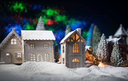 Christmas and New Year holidays concept. Little decorative cute small houses in snow at night. Traditional holiday attributes on snow. Creative artwork decorations. Empty space for your textの写真素材