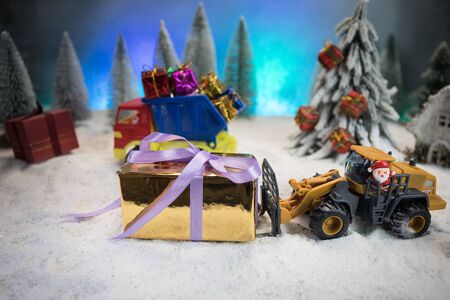 Miniature Gift Box by Forklift Machine on snow ,Determined Image for Christmas Holiday and Happy New Year Gift Celebration concept. Empty space for textの写真素材