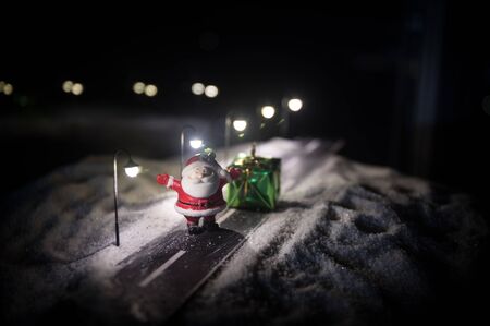 Little decorative cute small houses in snow at night in winter, Christmas and New Year miniature house in the snow at night with fir tree. Holiday concept. Selective focusの写真素材