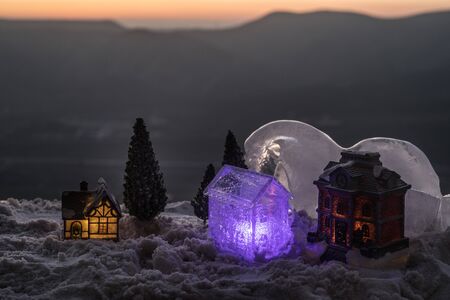 Christmas and New Year miniature house in the snow in the sunlight. Little toy house on snow with tree. Festive background. Christmas decorations. Holiday and celebration concept.の写真素材