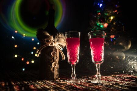 Glass of wine with Christmas decoration. Red wine in crystal glass with bottle on colorful carpet with creative New Year artwork decorations. Copy spaceの写真素材