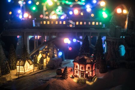Miniature of winter snowy scene with train on bridge, medieval castle and small city. Holiday attributes. Night scene. New Year and Christmas concept. Creative artwork mini on table decorationの写真素材