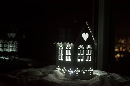 Little decorative cute small houses in snow at night in winter, Christmas and New Year miniature house in the snow at night with fir tree. Holiday concept. Selective focusの写真素材