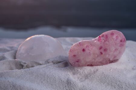 Beautiful ice heart figures on snow at sunset time. Winter holidays and love concept.