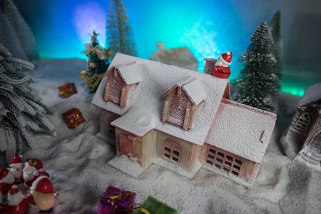 Christmas and New Year holidays concept. Little decorative cute small houses in snow at night. Traditional holiday attributes on snow. Creative artwork decorations. Empty space for your textの写真素材