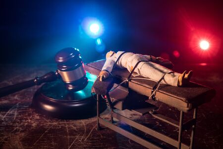 Lethal injection concept. Prisoner handcuffed to death by lethal injection. Creative artwork decoration with scale model on dark with lights.の写真素材