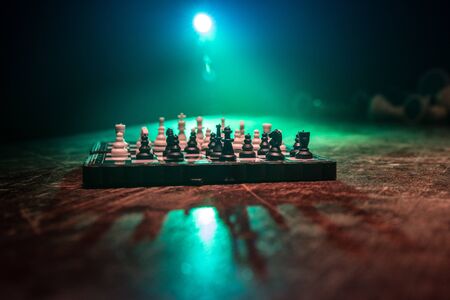 Chess board game concept of business ideas and competition. Chess figures on a dark background with...