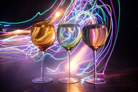 Goblet of wine on wooden table with beautiful toned lights on background. Glasses of wine on dark...