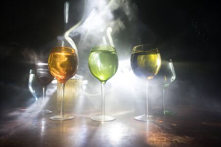 Goblet of wine on wooden table with beautiful toned lights on background. Glasses of wine on dark background. Selective focus. Club drink conceptの写真素材