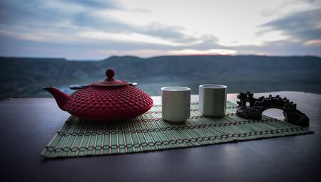 Tea concept. Japanese tea ceremony culture east beverage. Teapot and cups on table with bamboo on sunsetの写真素材