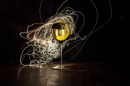 Goblet of wine on wooden table with beautiful toned lights on background. Glasses of wine on dark...