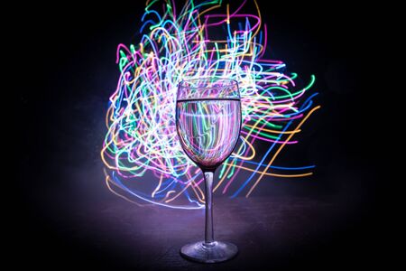 Goblet of wine on wooden table with beautiful toned lights on background. Glasses of wine on dark background. Selective focus. Club drink conceptの写真素材