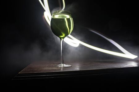Goblet of wine on wooden table with beautiful toned lights on background. Glasses of wine on dark background. Selective focus. Club drink conceptの写真素材