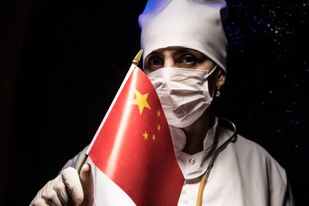 Woman doctor in mask holding Chinese flag.
