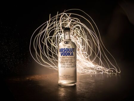 BAKU, AZERBAIJAN - FEB 09, 2020: Absolut Vodka is a brand of vodka, produced near Ahus, in Sweden. Owned by French group Pernod Ricard. Bottle of vodka on wooden table with dark toned foggy background.のeditorial素材