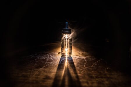 Vape concept. Smoke clouds and vape liquid bottles on dark background. Light effects. Useful as background or vape advertisement or vape background. Selective focusの写真素材