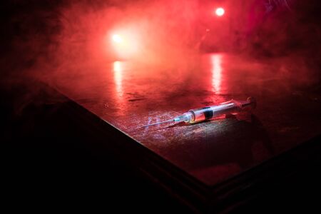 Narcotic drug problem concept. Drug syringe and narcotic attributes on wooden table. Purchase, possession and sale of drugs is punishable by law. Creative artwork decorationの写真素材