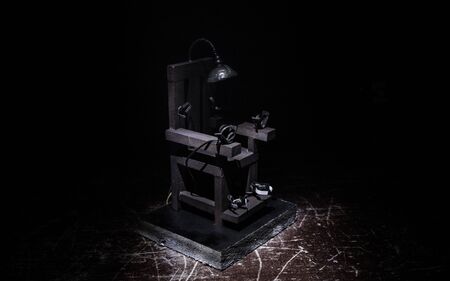 Death penalty electric chair miniature on dark. Creative artwork decoration. Image of an electric chair scale model on a dark backgorundの写真素材