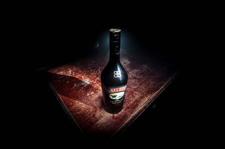 BAKU, AZERBAIJAN - FEB 09, 2020: Baileys Irish Cream is an Irish whiskey- and cream-based liqueur, made by Gilbeys of Ireland. A bottle of liqueur on wooden table with dark toned foggy background.のeditorial素材