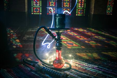 Hookah hot coals on shisha bowl making clouds of steam at Arabian interior. Oriental ornament on the...