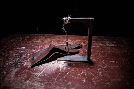Gallows, rope loop. The concept of suicide because of money. Empty purse on wooden table. Artwork...