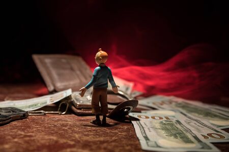 Money finance crime concept. Small human figurine standing on table with money. Creative artowkr...