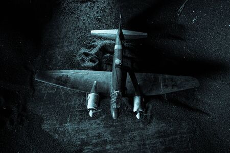 German Junker (Ju-88) night bomber at night. Artwork decoration with scale model of jet-propelled plane in possession. Toned foggy background with light. War scene. Selective focusの写真素材