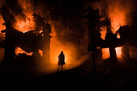 Old woman with cane in destroyed city. Terrible face of war concept. Creative artwork table decoration with light and fog. Selective focus.の写真素材