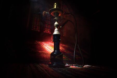 Hookah hot coals on shisha bowl making clouds of steam at Arabian interior. Oriental ornament on the...