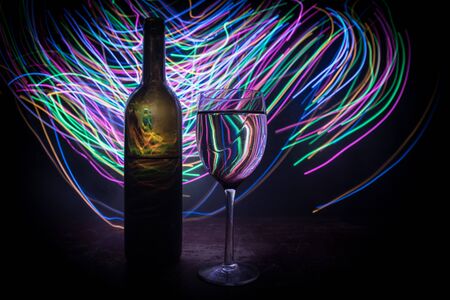 Goblet of wine on wooden table with beautiful toned lights on background. Glasses of wine on dark background. Selective focus. Club drink conceptの写真素材