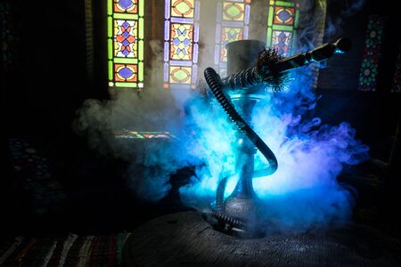 Hookah hot coals on shisha bowl making clouds of steam at Arabian interior. Oriental ornament on the...