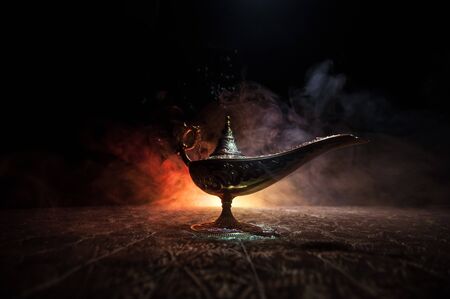 Antique Aladdin arabian nights genie style oil lamp with soft light white smoke, Dark background. Lamp of wishes conceptの写真素材