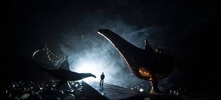 Lamp of wishes concept. Silhouette of a man standing in the middle of the road on a misty night with giant Antique Aladdin arabian nights genie style oil lamp. Creative artwork decorationの写真素材