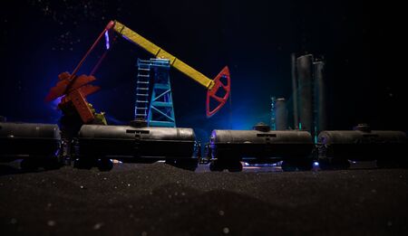Oil pump and oil refining factory at night with fog and backlight. Energy industrial concept. Night industrial railway with oil tank wagons. Selective focus. Artwork decoration.の写真素材