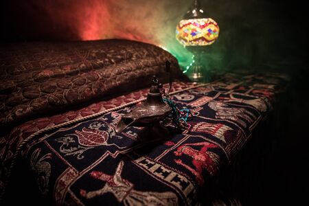 Antique Aladdin arabian nights genie style oil lamp with soft light white smoke, Dark background. Lamp of wishes conceptの写真素材
