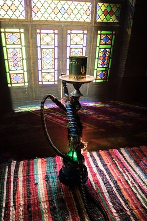 Hookah hot coals on shisha bowl making clouds of steam at Arabian interior. Oriental ornament on the...