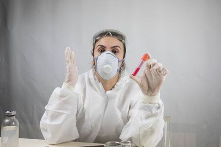 Coronavirus covid 19 infected blood vial in hand of female doctor with surgical mask and glows....