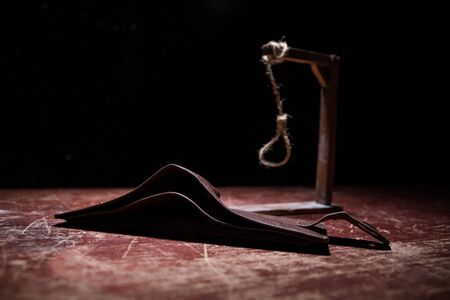 Gallows, rope loop. The concept of suicide because of money. Empty purse on wooden table. Artwork...