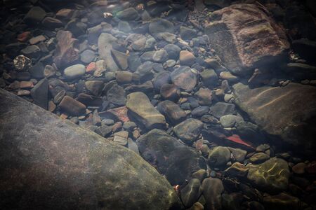 summer sunshine creates beautiful patterns on river stones under water. Nature shot