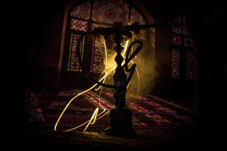 Hookah hot coals on shisha bowl making clouds of steam at Arabian interior. Oriental ornament on the...