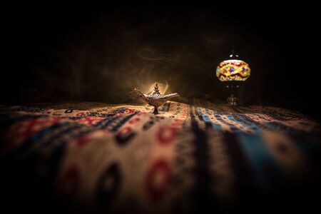 Antique Aladdin arabian nights genie style oil lamp with soft light white smoke, Dark background. Lamp of wishes conceptの写真素材