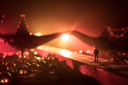 Lamp of wishes concept. Silhouette of a man standing in the middle of the road on a misty night with giant Antique Aladdin arabian nights genie style oil lamp. Creative artwork decorationの写真素材