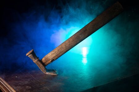 Old vintage hammer on a wooden table in front of a dark toned misty background. Selective focus.の写真素材