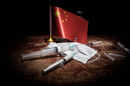 Corona virus concept. china put mask to fight against Corona virus. Concept of fight against virus. China flag and syringes on wooden tableの写真素材