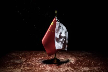 Corona virus concept. china put mask to fight against Corona virus. Concept of fight against virus. China flag and syringes on wooden tableの写真素材