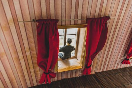 Sad, depressed man during the coronavirus quarantine staying at home, going mental and crazy. Covid-19 home isolation concept. Realistic dollhouse artwork decoration . Selective focusの写真素材