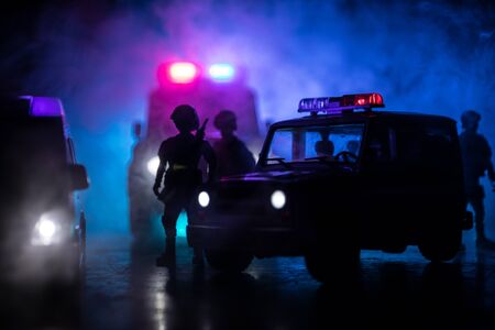 Corona virus concept with police. Stay home for precautionary measures to prevent from corona virus. Anti-riot police give signal to be ready. Smoke on a dark background with lights. Selective focusの写真素材