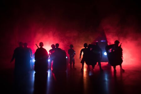 Corona virus concept with police. Stay home for precautionary measures to prevent from corona virus. Anti-riot police give signal to be ready. Smoke on a dark background with lights. Selective focusの写真素材