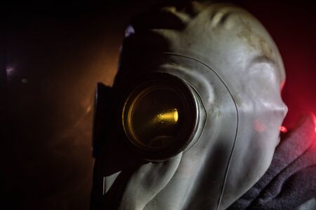 Environmental disaster. Post-apocalyptic survivor in gas mask on a dark background. Dramatic...