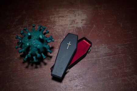 Creative artwork. Miniature wooden coffin on a table with dark background. Victims of coronavirus or...